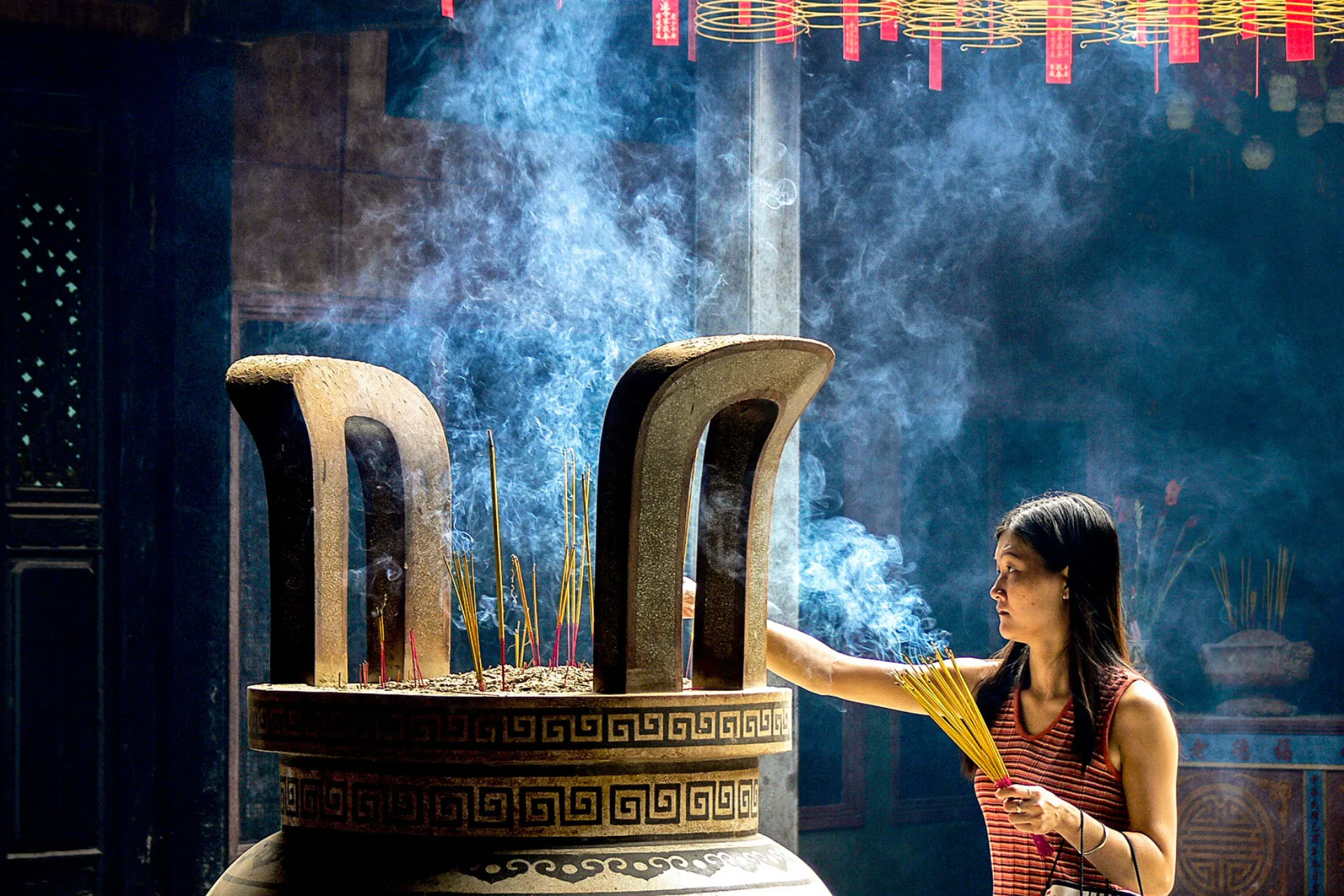 Nainen suitsuketikkujen kanssa Thien Haun temppelissä Nainen suitsuketikkujen kanssa Thien Haun temppelissä