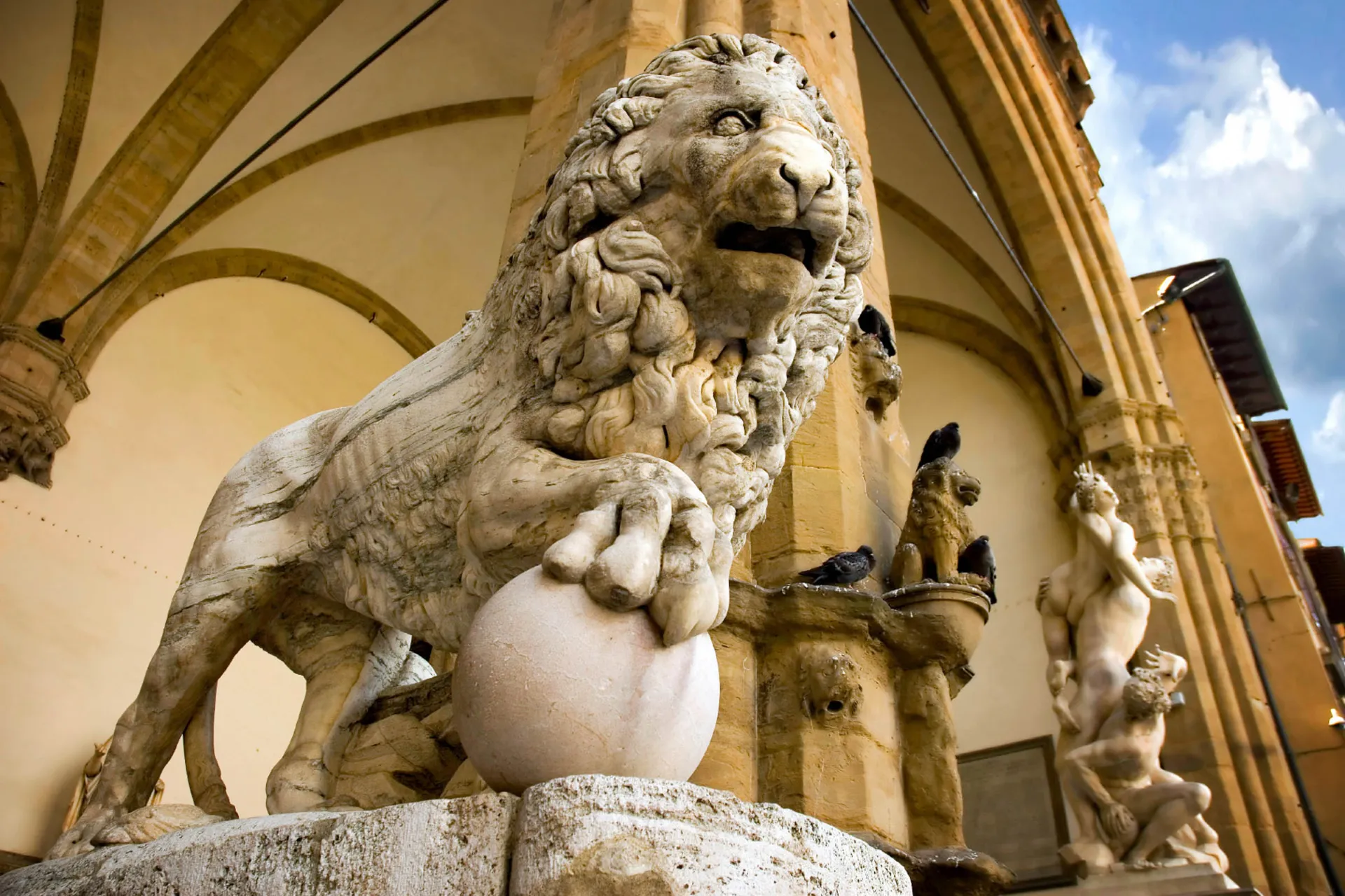 Marmorinen leijonaveistos taiteellisten yksityiskohtien ympäröimänä Marmorinen leijonaveistos taiteellisten yksityiskohtien ympäröimänä