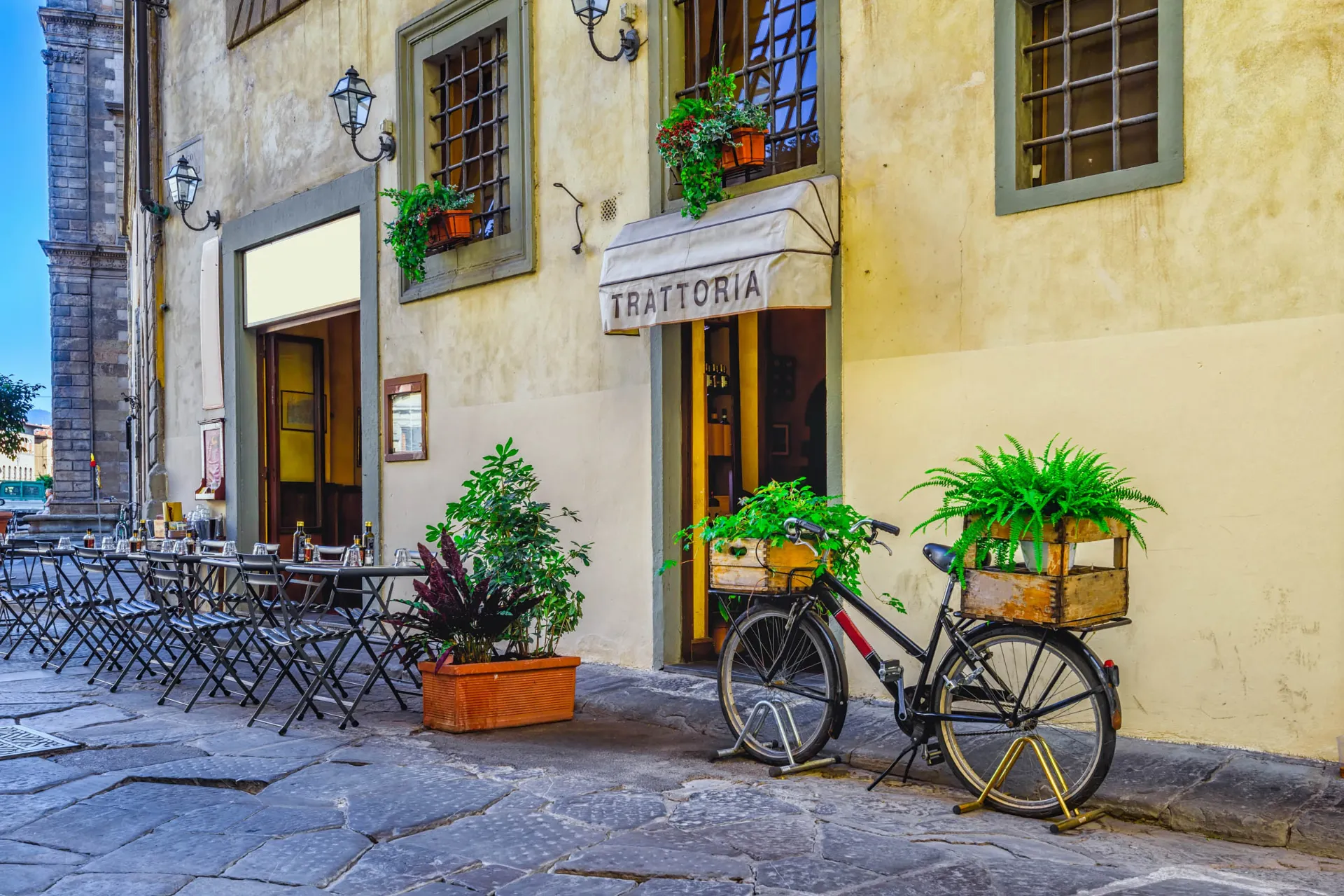 Trattoria ulkokahvilapöytineen ja kukilla koristellun polkupyörän kera Trattoria ulkokahvilapöytineen ja kukilla koristellun polkupyörän kera