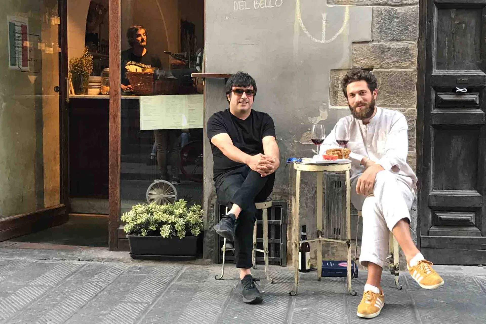 Kaksi miestä nauttii lasillisen viiniä pienessä pöydässä kadulla Kaksi miestä nauttii lasillisen viiniä pienessä pöydässä kadulla