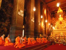 Munkit rukoilemassa kultaisen Buddhan edessä Wat Pho -temppelissä, Bangkok