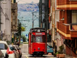 Ikoninen punainen raitiovaunu kiemurtelee kaupungin katuja Bosporin taustalla