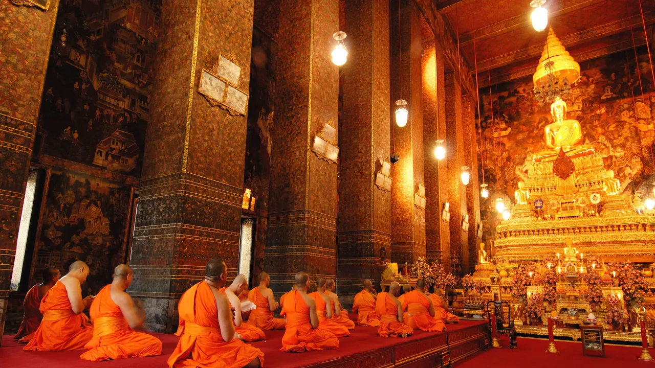 Munkit rukoilemassa kultaisen Buddhan edessä Wat Pho -temppelissä, Bangkok